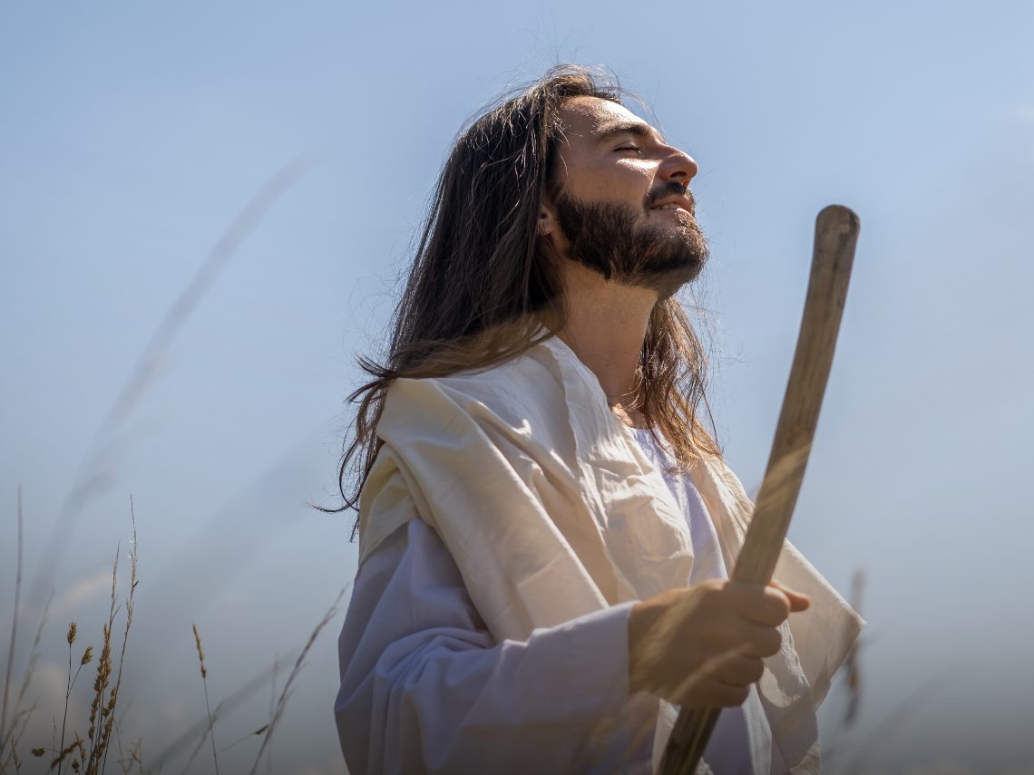 Jesus Christ holding a shepherd's staff in a field